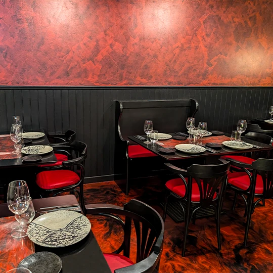 Interior of Inferno Gastro Bar with elegantly set tables, highlighting the contrast between the red of the seats and the black of the decoration, creating a cozy and sophisticated atmosphere.
