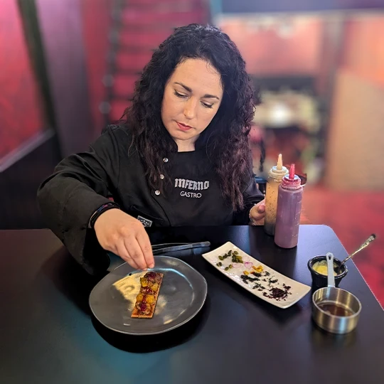 Chef of Inferno Gastro Bar adding the finishing touches to crispy sweetbreads with creamy potato and lemon caramel, highlighting the attention to detail in the dish’s presentation.