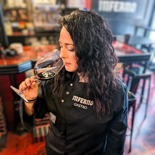 Sommelier of Inferno Gastro Bar tasting a red wine, showing the attention and experience in the selection and tasting of the restaurant's wines.